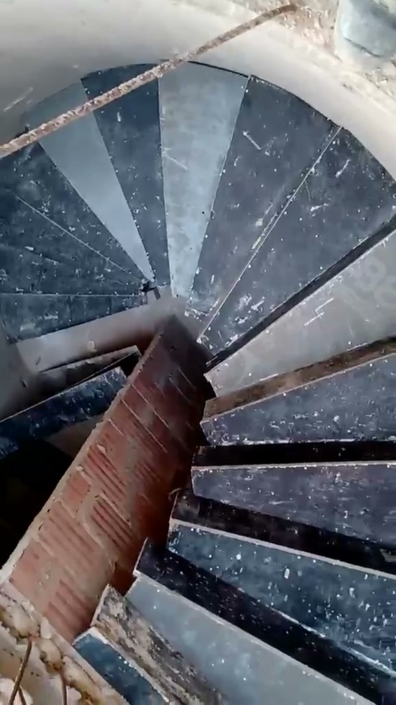 Escada em caracol vista de cima, com degraus escuros