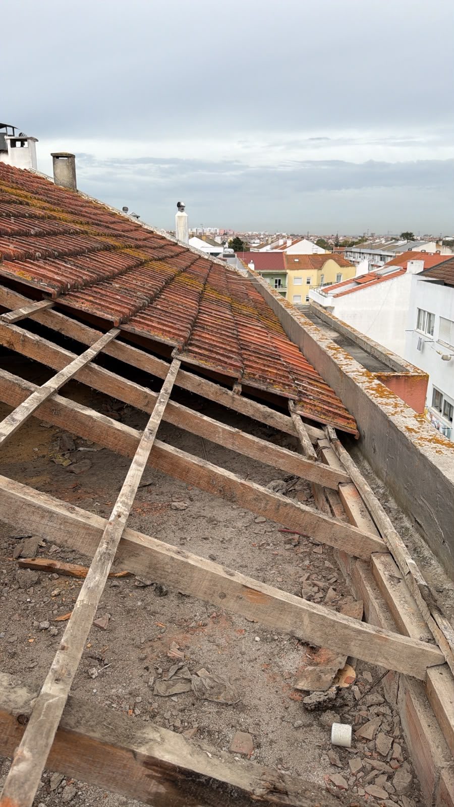 Telhado em obra, com parte das telhas retirada e a estrutura de ripas à vista